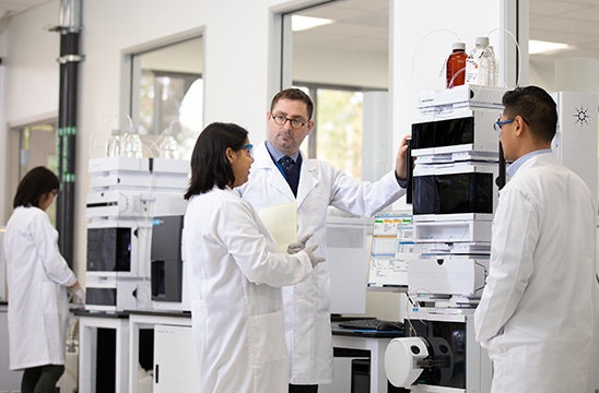 Photo of scientists in a lab over an Agilent machine