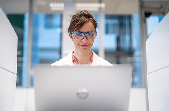 Photo of a scientist with safety goggles at her laptop