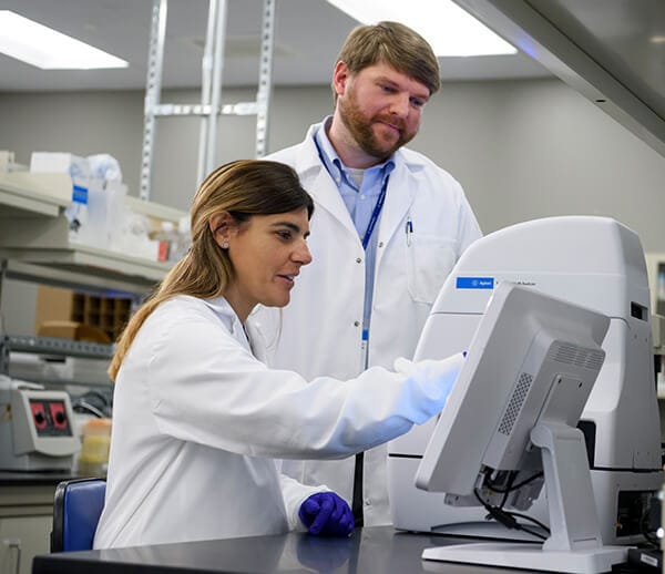 Two lab scientists with an Agilent Seahorse XF analyzer