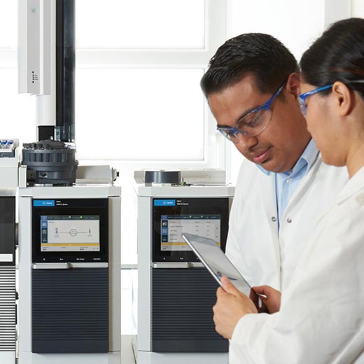 Two scientists looking at tablet in front of Intuvo 9000 GC