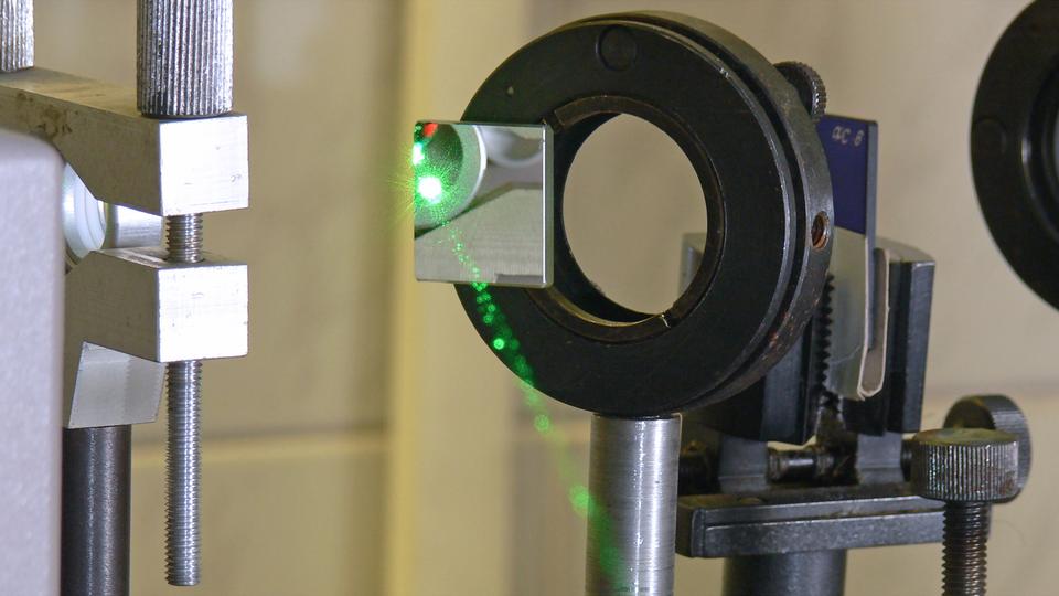 A green laser is reflected from an angled mirror