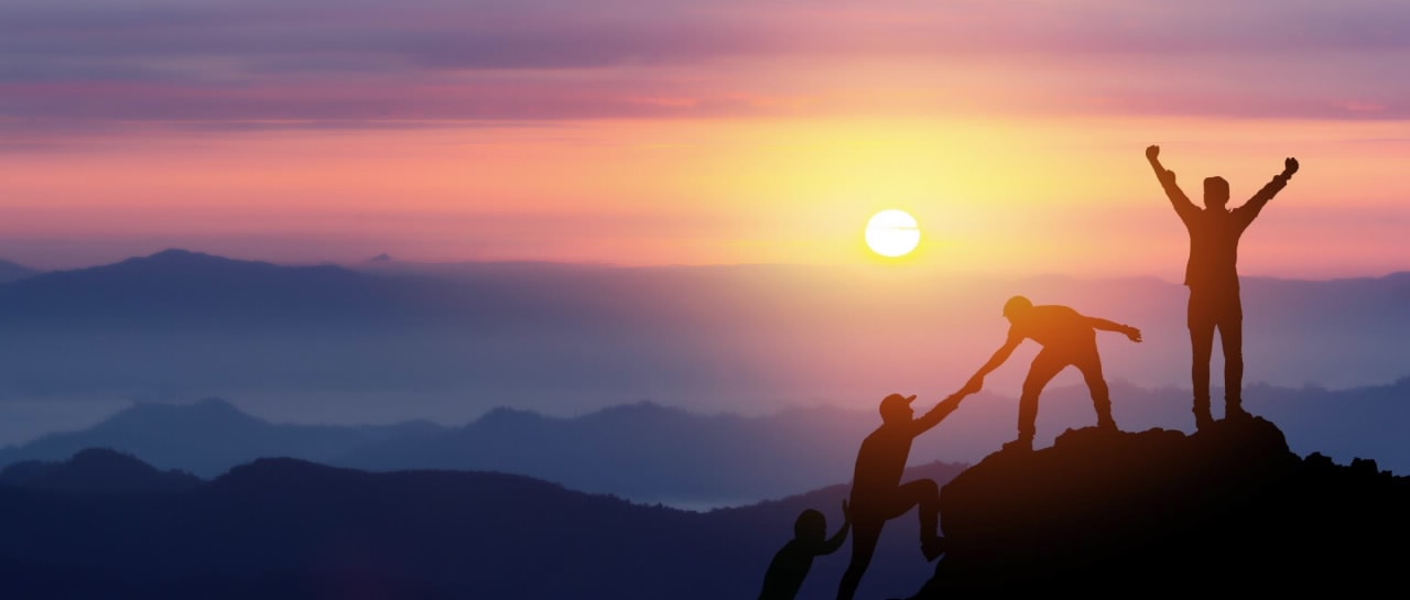 People celebrating on a mountain at sunrise