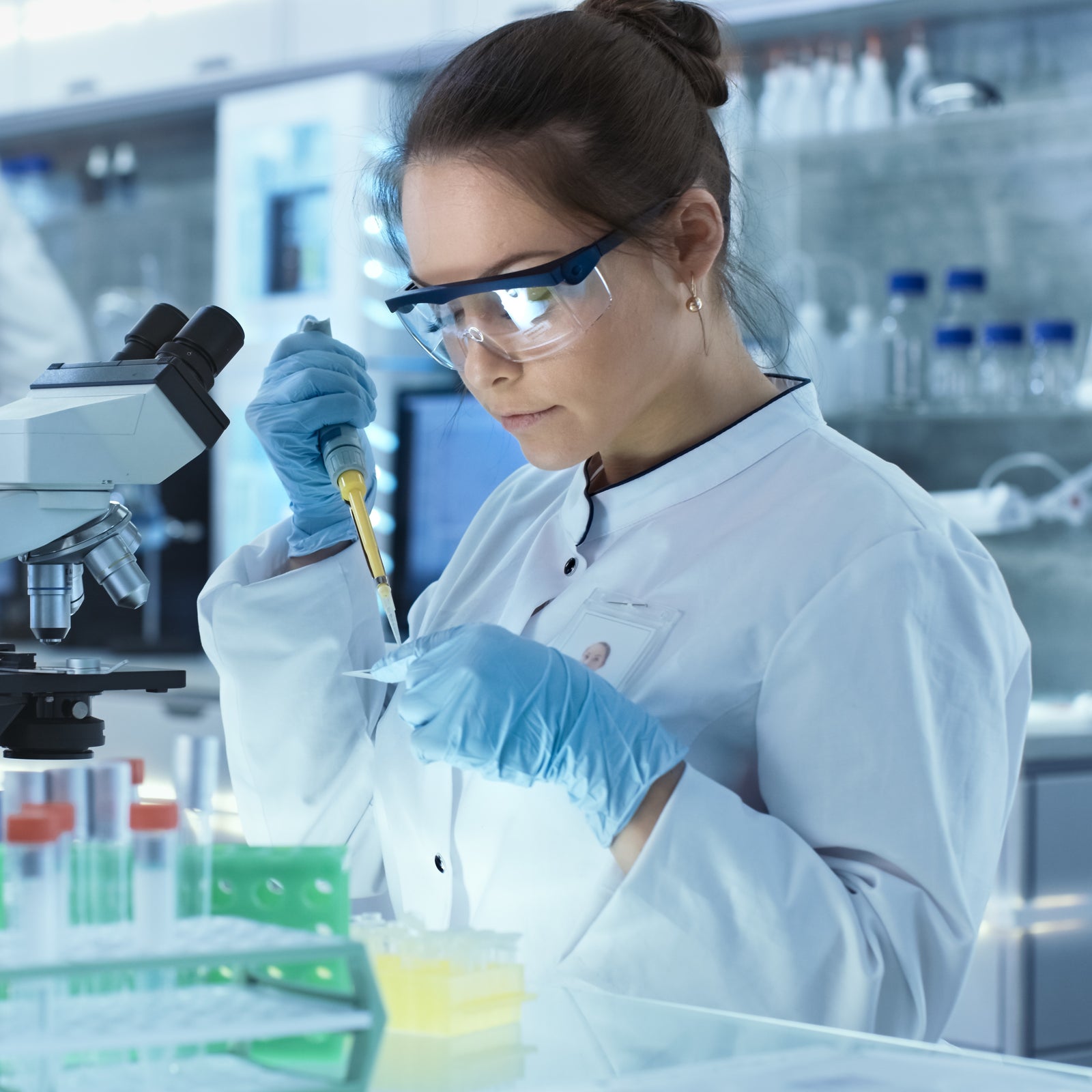 Scientist with micropipette filling test tubes