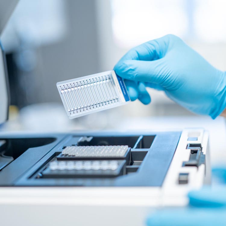A hand in a blue glove holds a High Sensitivity Genomic NA ScreenTape assay, which is used with Agilent Tapestation systems to streamline NGS workflows.